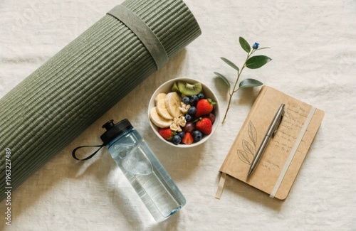 Minimalist flat lay with yoga mat, water bottle, healthy snack and journal. Organized wellness elements on light background. Perfect for lifestyle planning and balanced living content.