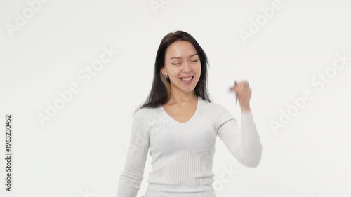 Young adult woman holds the keys to buying a car or apartment white background isolated space happy