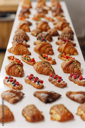 Assorted croissants and pastries arranged in neat rows on a bakery display for breakfast catering