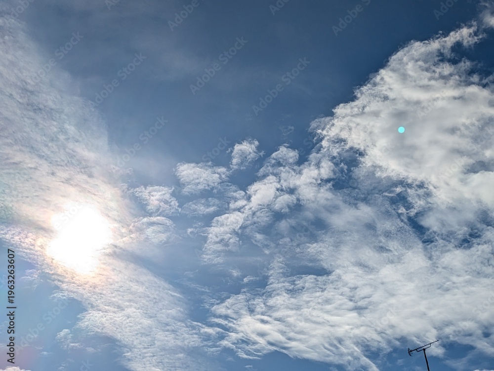 Obraz premium Beautiful blue summer air with fluffy white clouds and chem trail lines across the sky