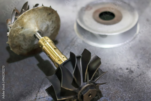 Принти на полотні Close-up of a high-performance turbocharger shaft assembly with turbine wheel and compressor impeller on a metal workbench in a professional mechanical workshop