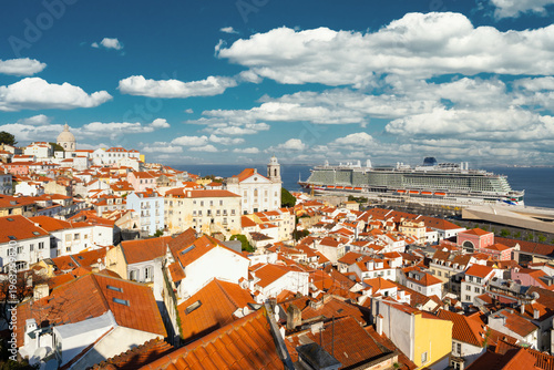 Alfama Oldest Historic Neighborhood and Cruise Ship on Sunny Day. Red Roofs and Old White Houses. Lisbon, Portugal. View from Miradouro das Portas do Sol