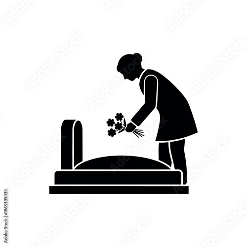 Woman placing flowers on a grave.
