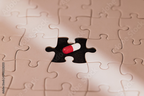 Symbolic view of a white puzzle and a bright pill in the missing space under a light beam over black background for health success.