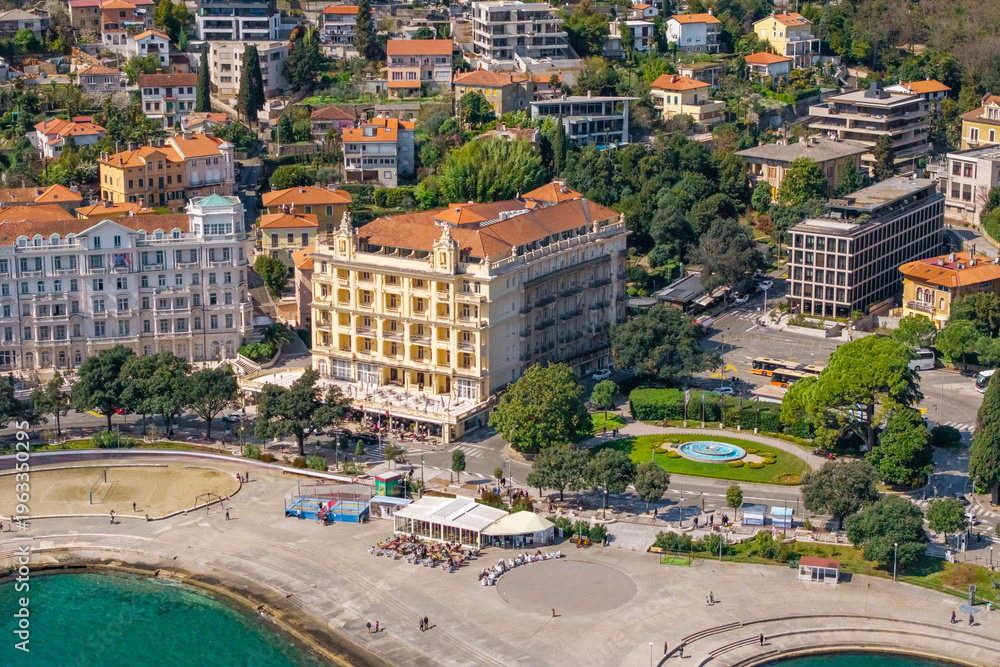Fototapeta premium Aerial coastal view of Opatija waterfront with grand historic hotels, promenade, small beach area and urban square with fountain