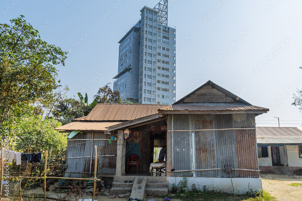 Fototapeta premium The Life of an Average Poor A modest tin shelter in the foreground contrasts sharply with a towering modern skyscraper behind it, highlighting the gap between everyday struggle and rapid urban growth.