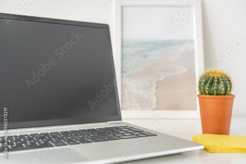 geöffneter Lap top im Büro mit Pflanze auf dem Schreibtisch - Remote Office