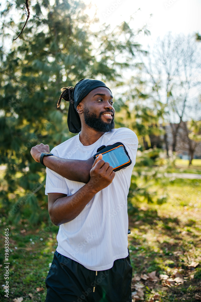 Fototapeta premium Smiling Black male runner checking smartwatch