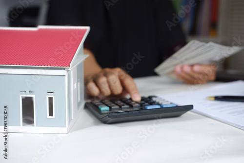 Miniature houses and calculating budgets with a calculator. Financial planning concepts for insurance, credit, and housing maintenance. Real estate
