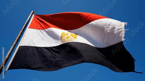 Egyptian flag waving in the wind against a clear blue sky