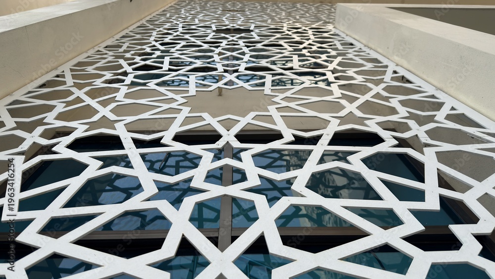 Obraz premium Extensive White Geometric Pattern Screen on a Building Facade with Reflective Windows
