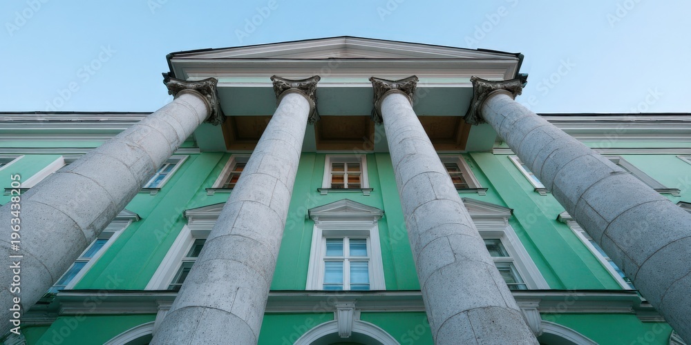 Obraz premium Turquoise neoclassical building with white columns, arched windows, towering portico and dramatic low angle perspective of mint green facade