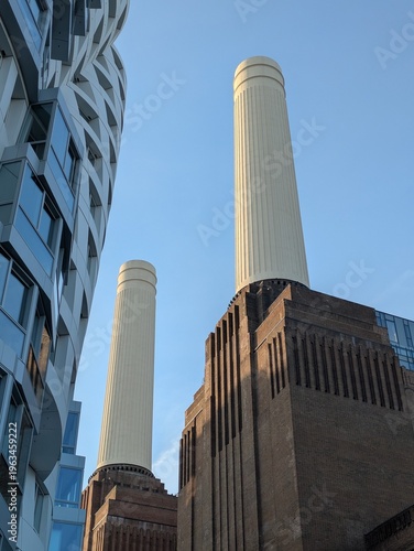 The iconic Battersea Power Station with its distinctive chimneys, framed by modern architecture, showcasing the blend of history and innovation in urban design.
