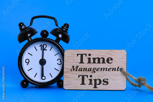 Time Management Tips Concept with black alarm clock on blue background