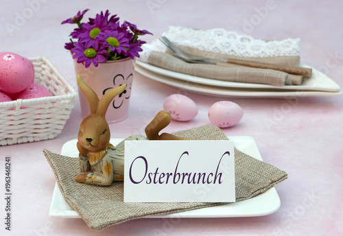 Festliche Tischdeko zum „Osterbrunch“ mit Platzkarte, lila Blumen und Osterhase auf rosa Hintergrund.