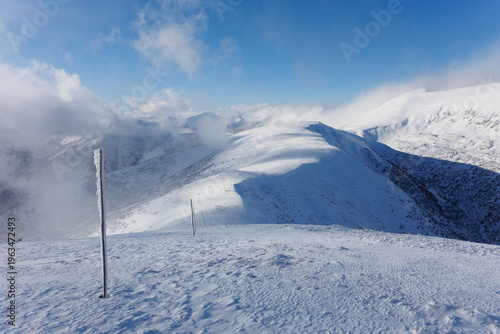 View from Besna, Low Tatras, Nizke Tatry, Slovakia. Beautiful winter landscape of mountains is covered by snow in wintertime. Sunny weather with mist, fog and clouds.