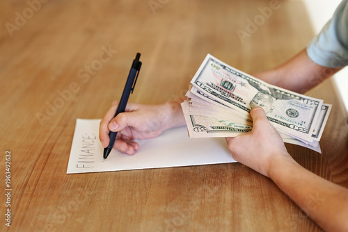 Close up hands holding and counting US dollar banknotes while writing finance on paper. Concept of budgeting, planning expenses, personal finance management, savings and everyday money control