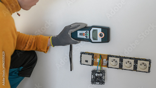 Electrical installation. The electrician's hand using a wall scanner for checking electrical wires in the wall. Metal detector.