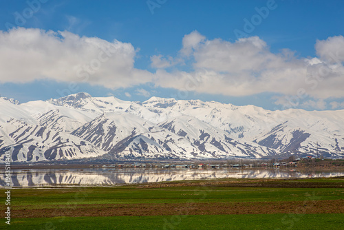 A village nestled at the foot of the mountains in the Yüksekova district of Hakkari province, and the snow-capped mountains are reflected in the water.