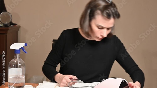 Young woman doing electric manicure with nail drill at home