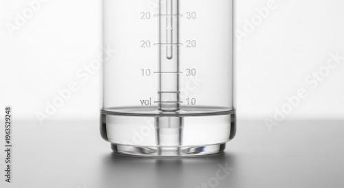 Close-up of a clear glass volumetric measuring device containing transparent liquid, essential for accurate laboratory experiments and precise scientific work.