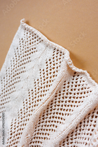 Картината върху платно Folded light knitted fabric with openwork pattern on neutral background