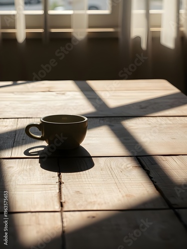 A coffee cup sits on a wooden table in a room with natural light
