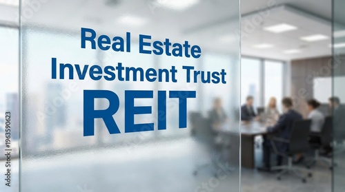 Real Estate Investment Trust REIT sign on a glass office wall with a business meeting in the background.