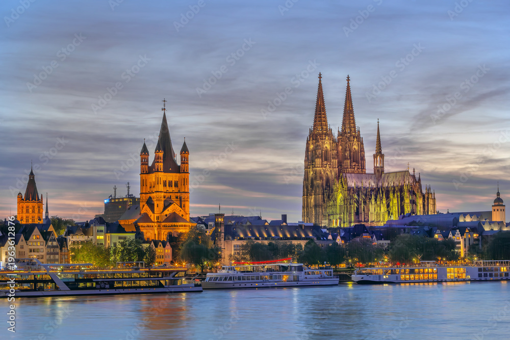 Fototapeta premium Cologne historical center with cathedral and Saint Martin view at evening from Rhine in Germany. Illuminated city architecture