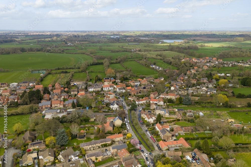 Fototapeta premium Angled aerial view of Bishop Monkton showing houses gardens roads and surrounding farmland creating a scenic rural village landscape in North Yorkshire during the spring time countryside setting