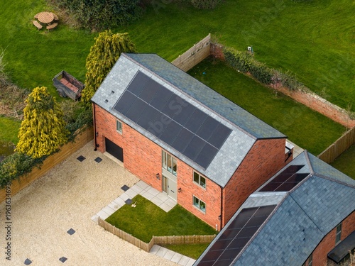 Aerial view of a modern brick house in Bishop Monkton with solar panels gravel driveway garden, fenced outdoor space showing sustainable rural living in North Yorkshire village setting in the spring