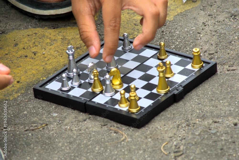 Φωτογραφία Person's hand moving a piece on a mini magnetic chess board outdoors