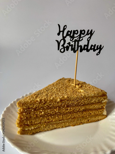 Canvas Print a piece of delicious cake on a white plate on a white background, happy birthday
