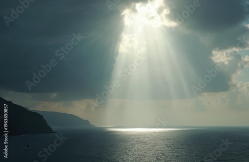 Sun rays pierce dark clouds over calm ocean waters, illuminating sea surface. A lone sailboat navigates near hilly coast. Dramatic natural light breaks through stormy weather.