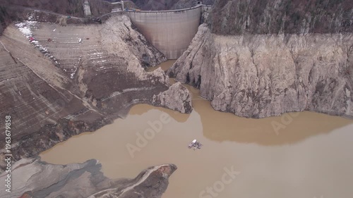 Low water level at Vidraru Dam in the Carpathian Mountains on a cloudy day