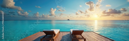 Two empty lounge chairs on wooden deck facing calm turquoise ocean water at sunset. Island in distance under bright sky with scattered clouds, peaceful vacation scene.