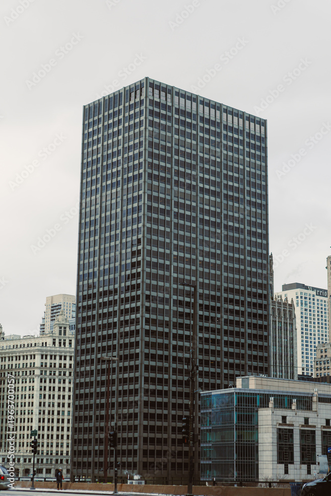 Obraz premium Modern office building stands tall in a busy city center during an overcast day