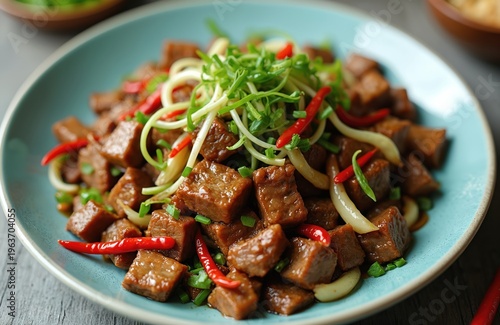 Diced beef stir-fried with garlic sprouts and red chili peppers. Savory asian cuisine served on blue plate. Delicious food for lunch or dinner.