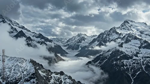 Majestic snow-capped peaks and foggy valley under cloudy sky