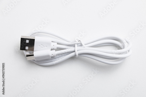 White charging and data sync cable USB-C to USB tied up isolated on light background, clean aesthetic tech accessory close-up
