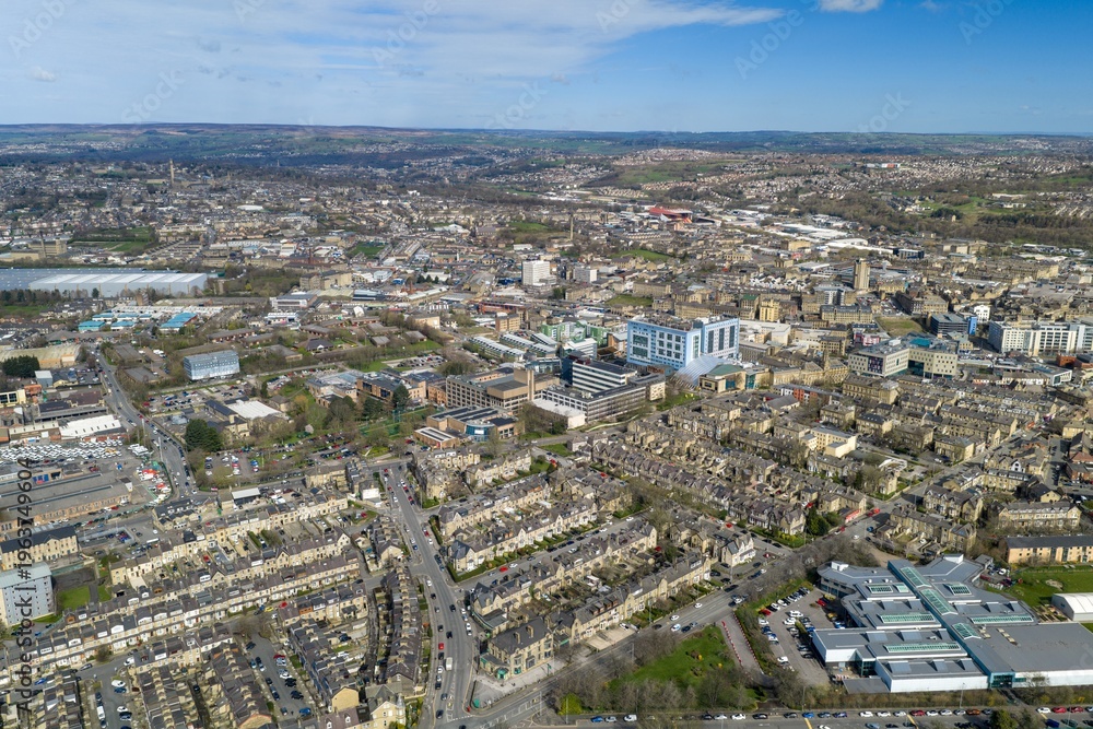 Fototapeta premium Aerial drone view of the city of Bradford cityscape in West Yorkshire showing dense housing industrial zones and roads stretching across the landscape with distant hills in the daytime