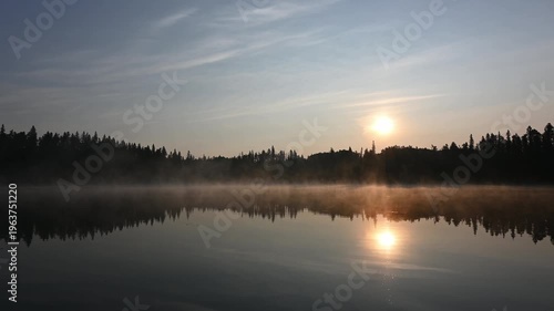 View Across a Calm Northern Park Lake as Morning Sun Lights Up Mist Over a Peaceful Reflective Water Landscape.