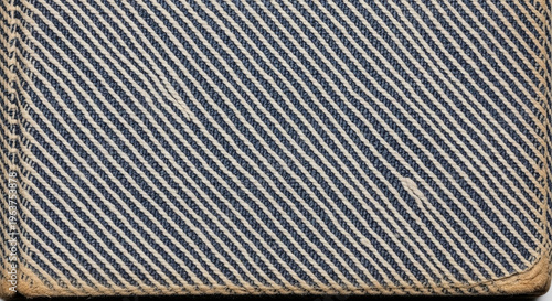 Close-up of a vintage textured denim fabric with diagonal ribbing and frayed edges on a white background, highlighting blue and white threads interwoven in a classic casual fashion material