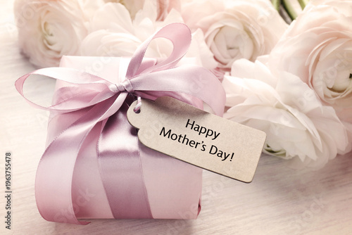 Happy Mother's Day. Gift box with tag and bouquet of ranunculus flowers on table, closeup
