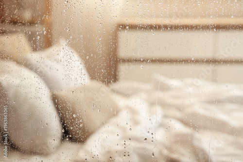 Foto Water droplets on glass against blurred bed in room, closeup
