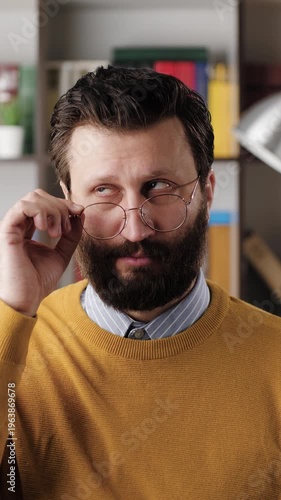 Skepticism, sarcasm emotion. Vertical video of bearded man in glasses in office or apartment room expressing his skeptical attitude and discontent with his look