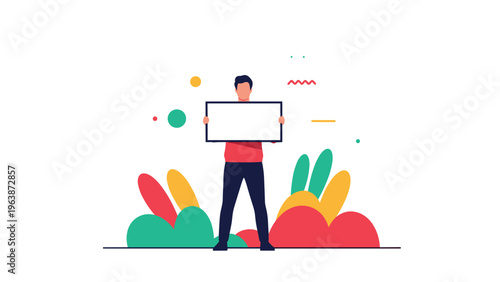 Young man standing among colorful abstract plant shapes holding a small blank white rectangular sign for a message.