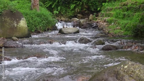 Clear river flow with refreshing scenery, showing crystal water, natural stones, and calming atmosphere in a serene tropical landscape