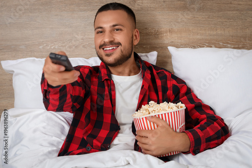 Young man with popcorn watc...