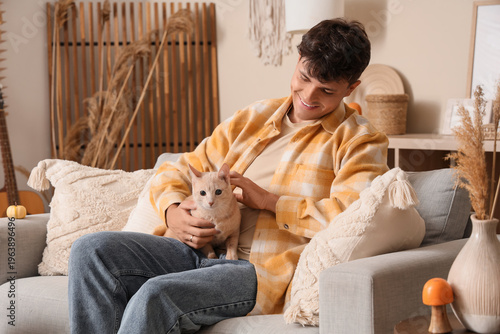 Young man with cute cat sit...